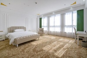 A spacious bedroom with a large bed, a chair, a desk, and a window with green curtains.