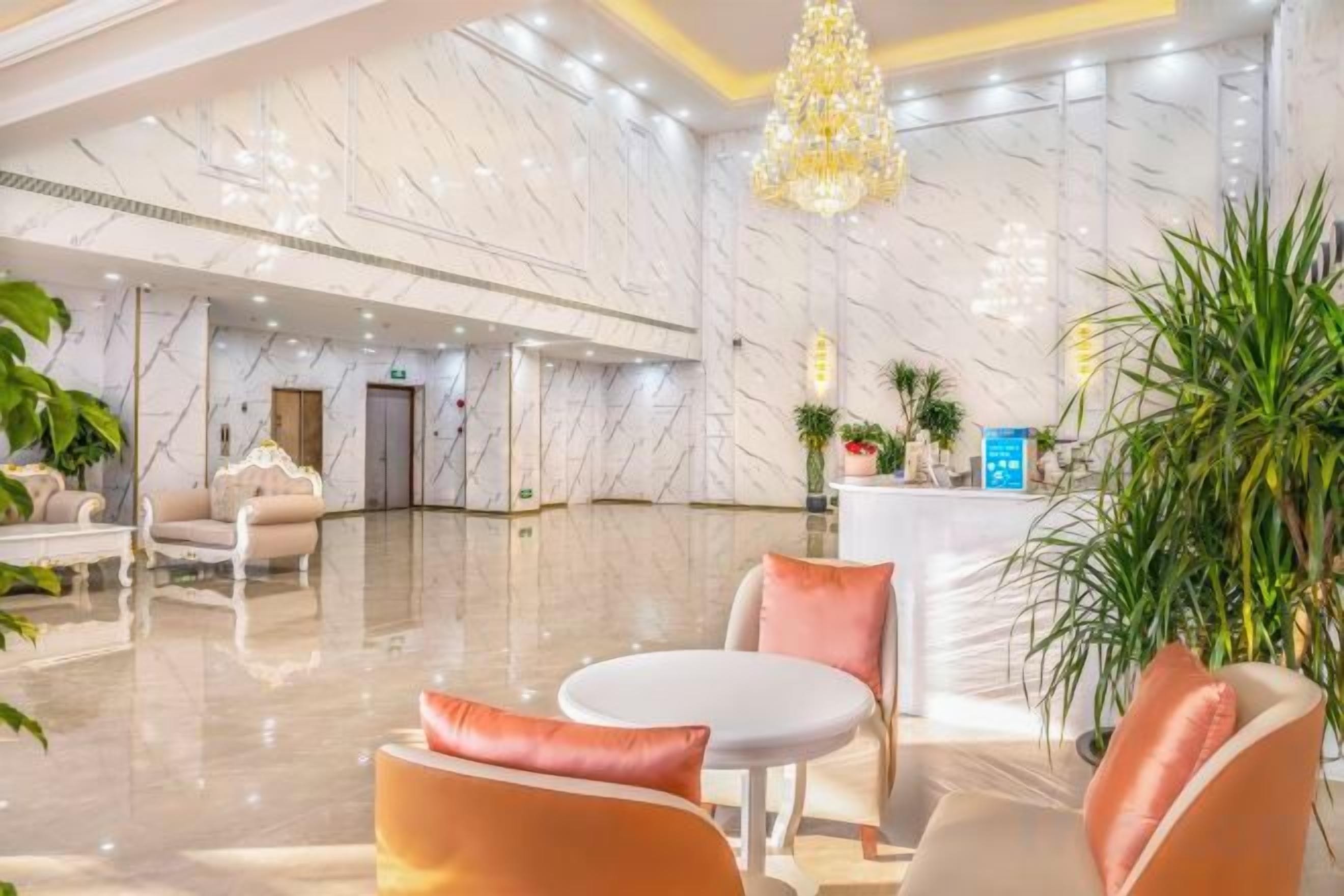 A hotel lobby with marble walls, a reception desk, and seating areas.