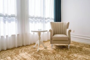 A room with a patterned carpet, a cream-colored armchair, a small white table, and sheer curtains. - Lanting Hotel (MixC Baimajing Road Metro Station Branch ) (Kushan)