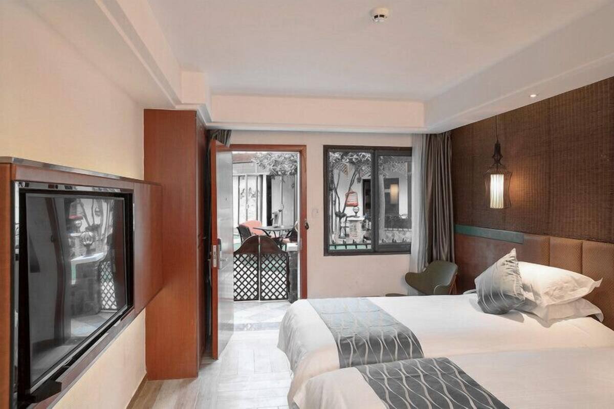 A hotel room with a bed, a TV, and a view of the outside.