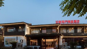 Un hotel de estilo chino tradicional con un letrero rojo, alfombra roja y estatuas de piedra.