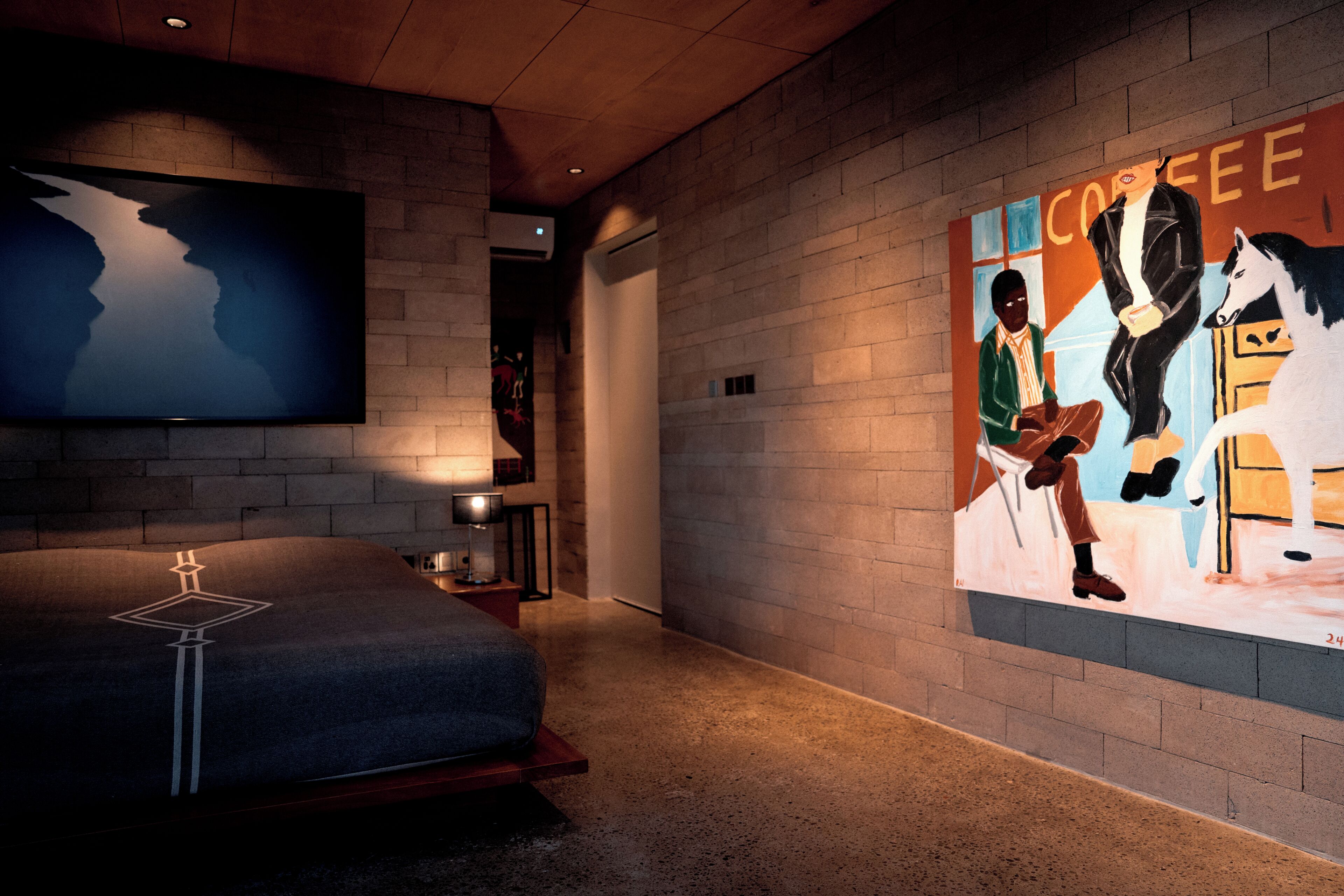 Une chambre d’hôtel avec un lit, un tableau, une fresque murale sur le thème du café et un téléviseur.