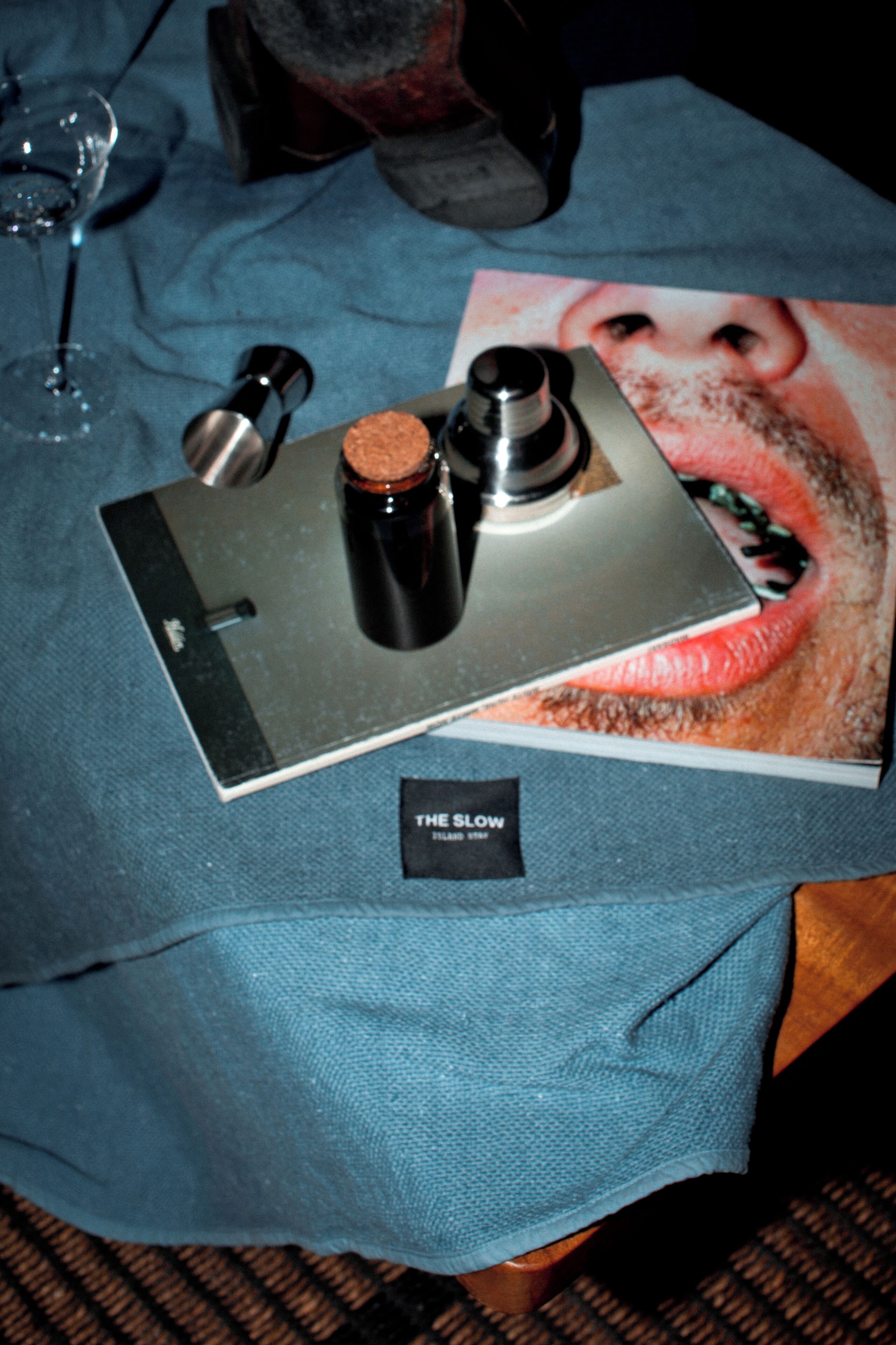A table with a book, a bottle, and a metal object on a blue cloth.