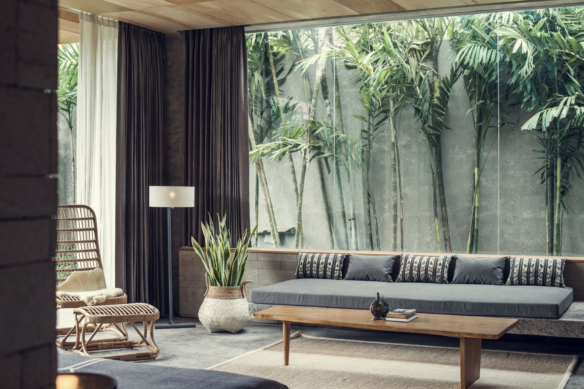 A modern living room with a large window, a sofa, a coffee table, a floor lamp, and a chair.
