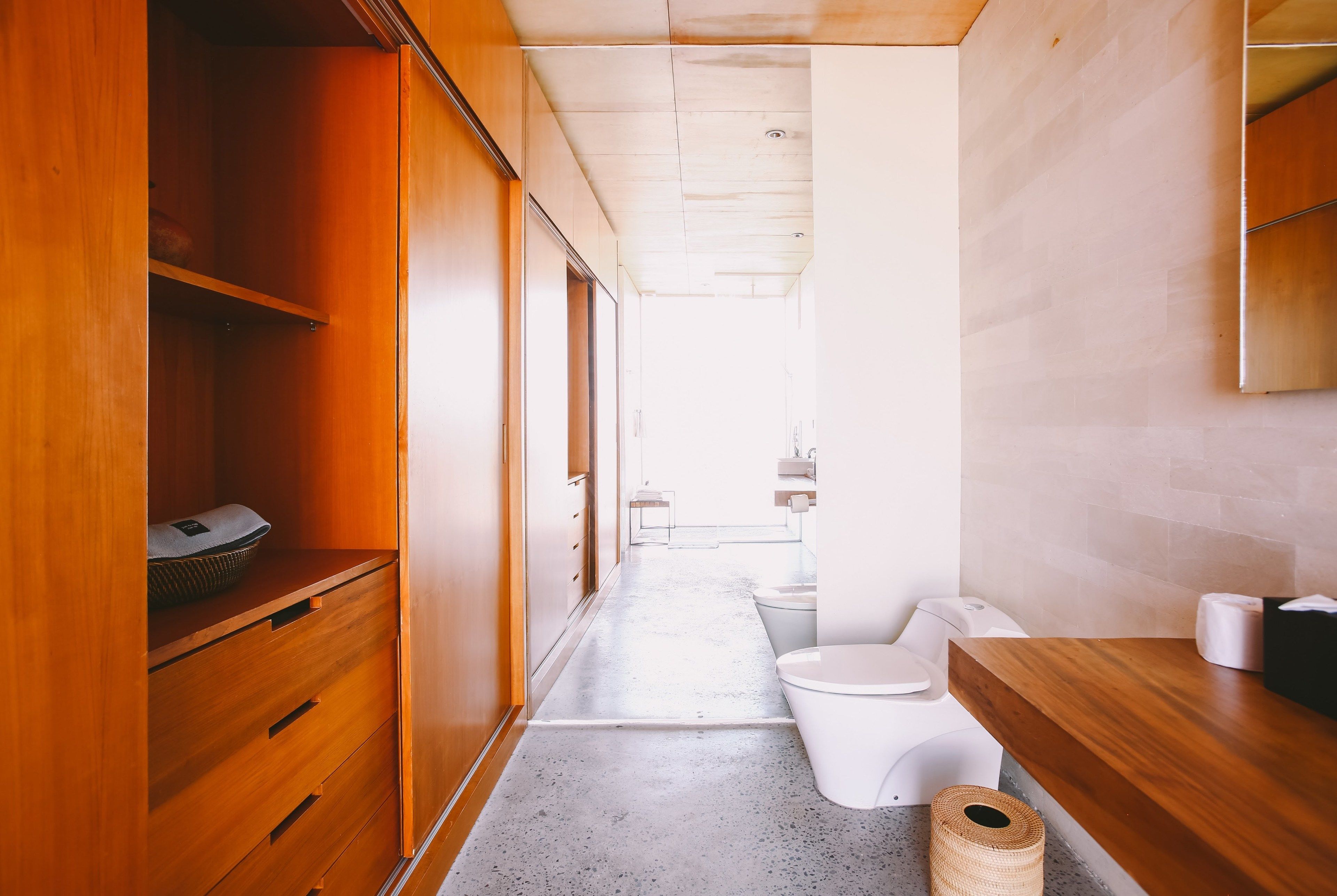 A narrow hallway with wooden cabinets and a white toilet.