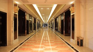 A long, well-lit hallway with marble flooring and doors on both sides, leading to a distant exit. - Country Garden Phoenix Hotel, XingAnMeng (Xing'an)
