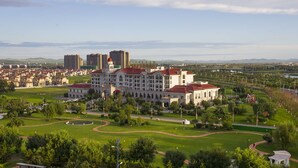 A large building with multiple floors and a red roof, surrounded by green lawns and pathways. - Country Garden Phoenix Hotel, XingAnMeng (Xing'an)