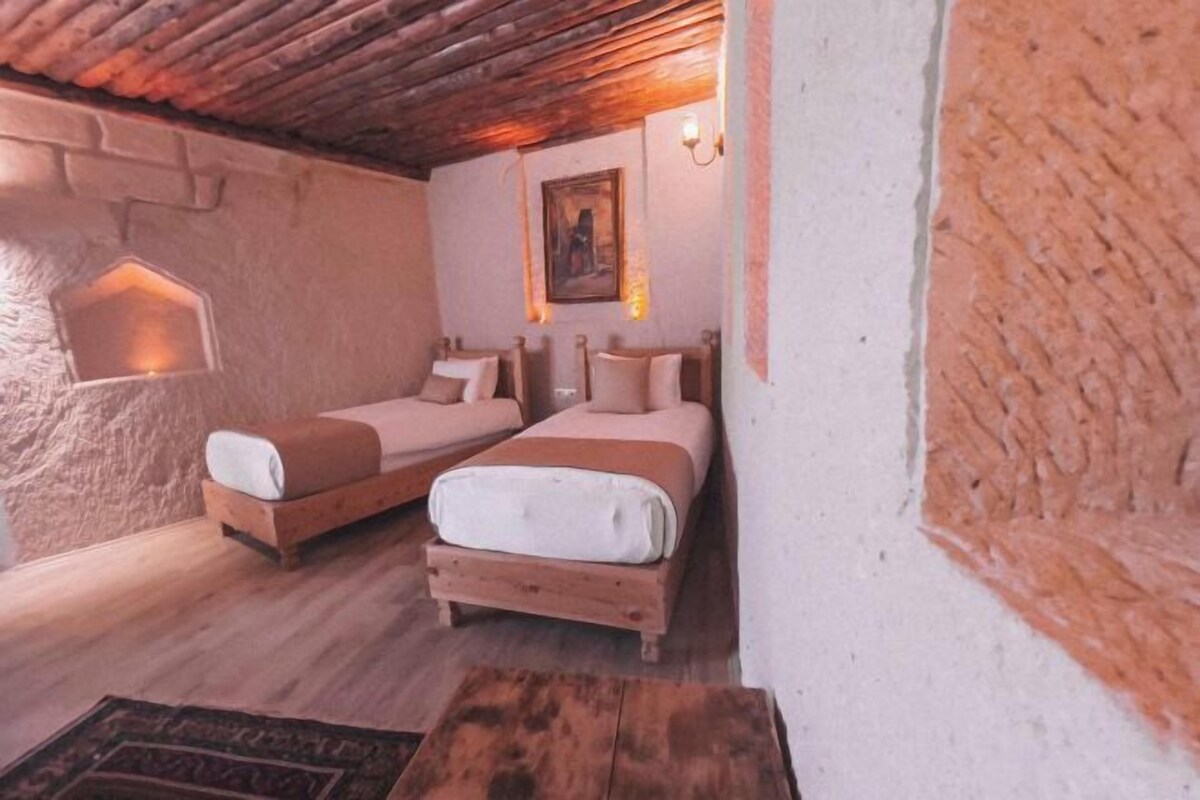 Une chambre rustique avec deux lits en bois, une petite fenêtre et un tableau accroché au mur.