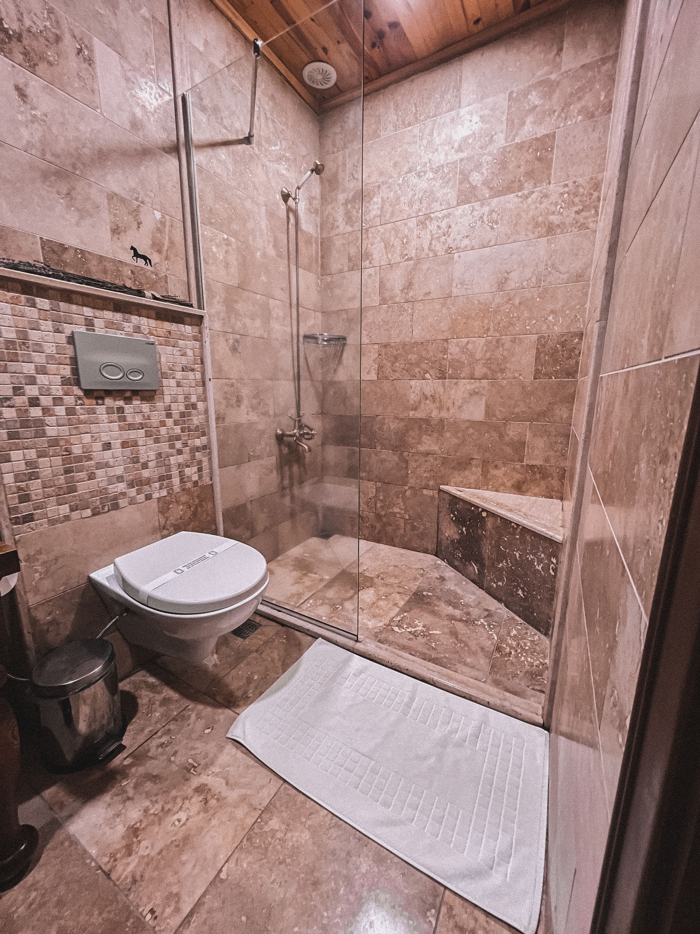 A bathroom with a glass-enclosed shower, a toilet, and a sink.