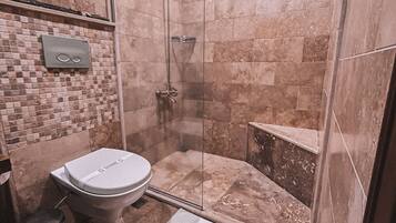 A bathroom with a glass-enclosed shower, a toilet, and a sink.