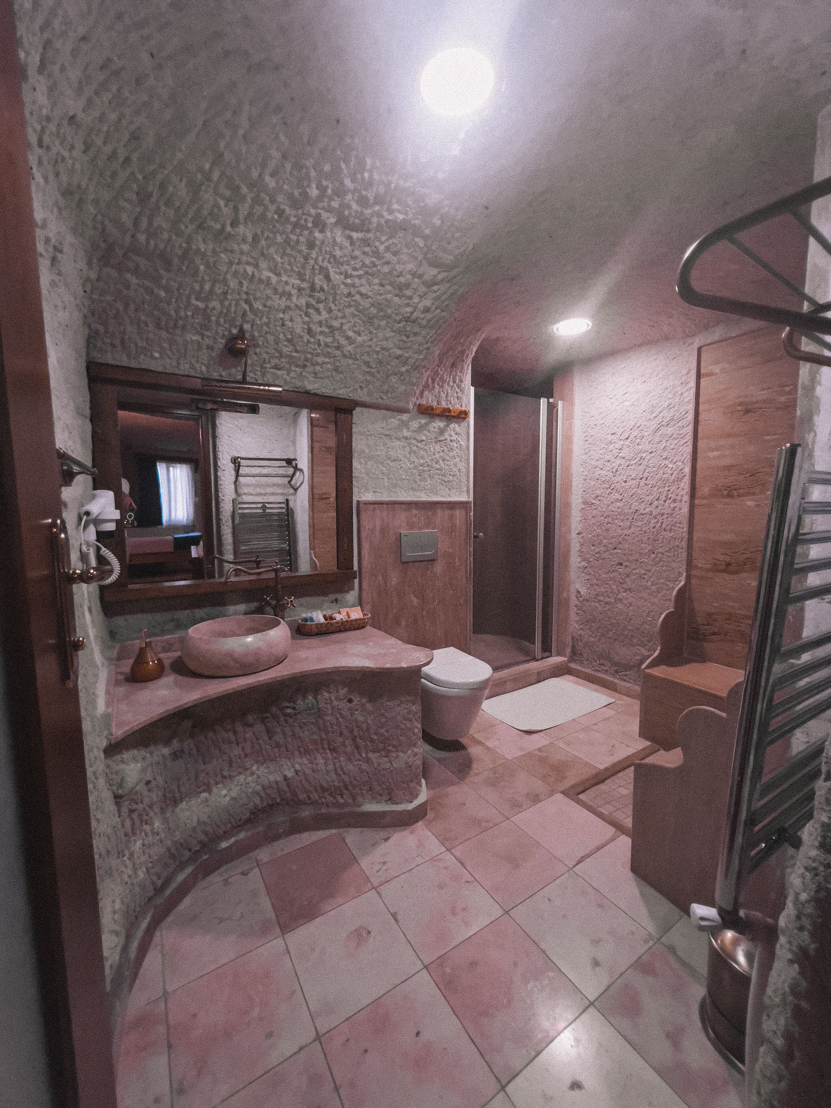 A bathroom with a stone wall, a sink, a toilet, and a shower.