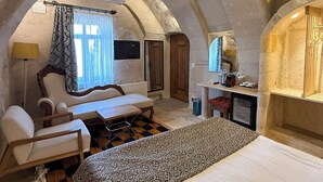 A cozy, arched room with a bed, a desk, a chair, and a television. - Local Cave House Hotel (Nevsehir)