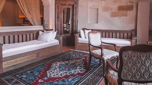 A traditional room with a wooden bench, a patterned rug, and a chandelier. - Local Cave House Hotel (Nevsehir)