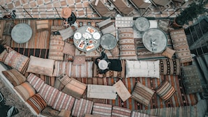 An outdoor seating area with patterned cushions, round tables, and chairs arranged on a tiled floor. - Local Cave House Hotel (Nevsehir)