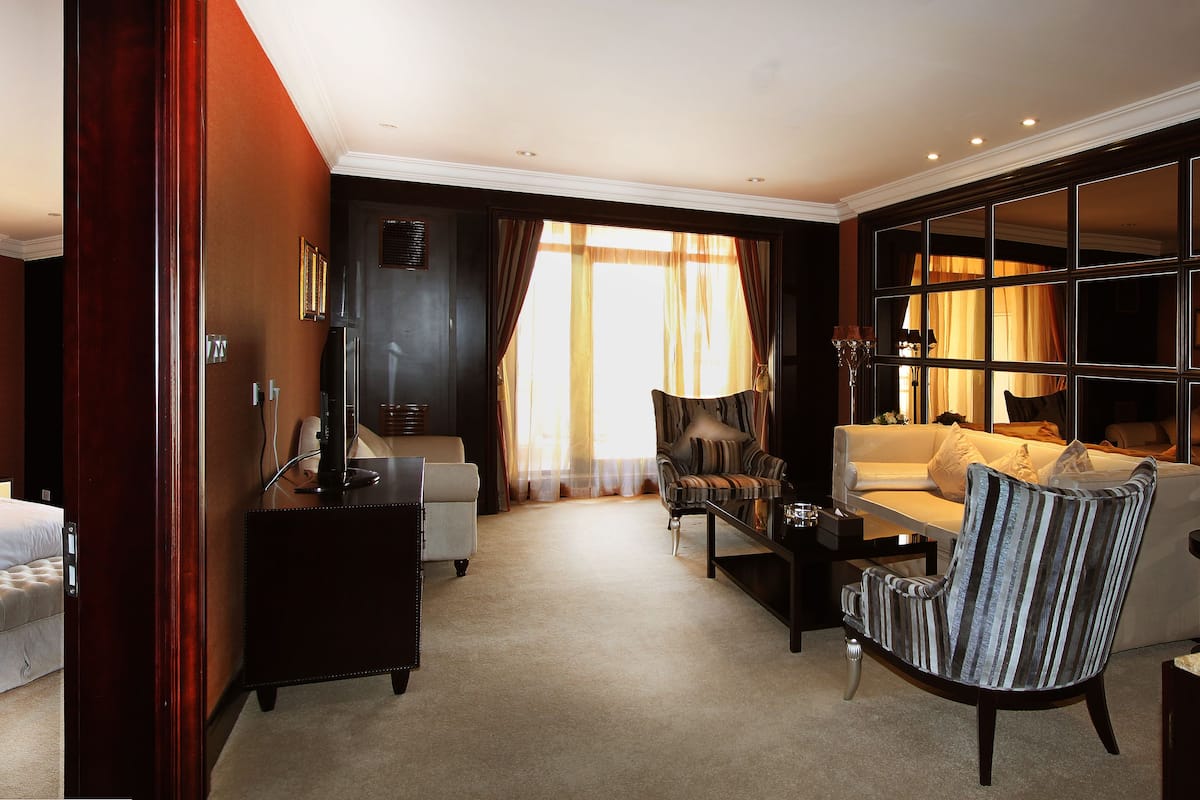 Une chambre d’hôtel avec un grand lit, un canapé, un fauteuil et un bureau.
