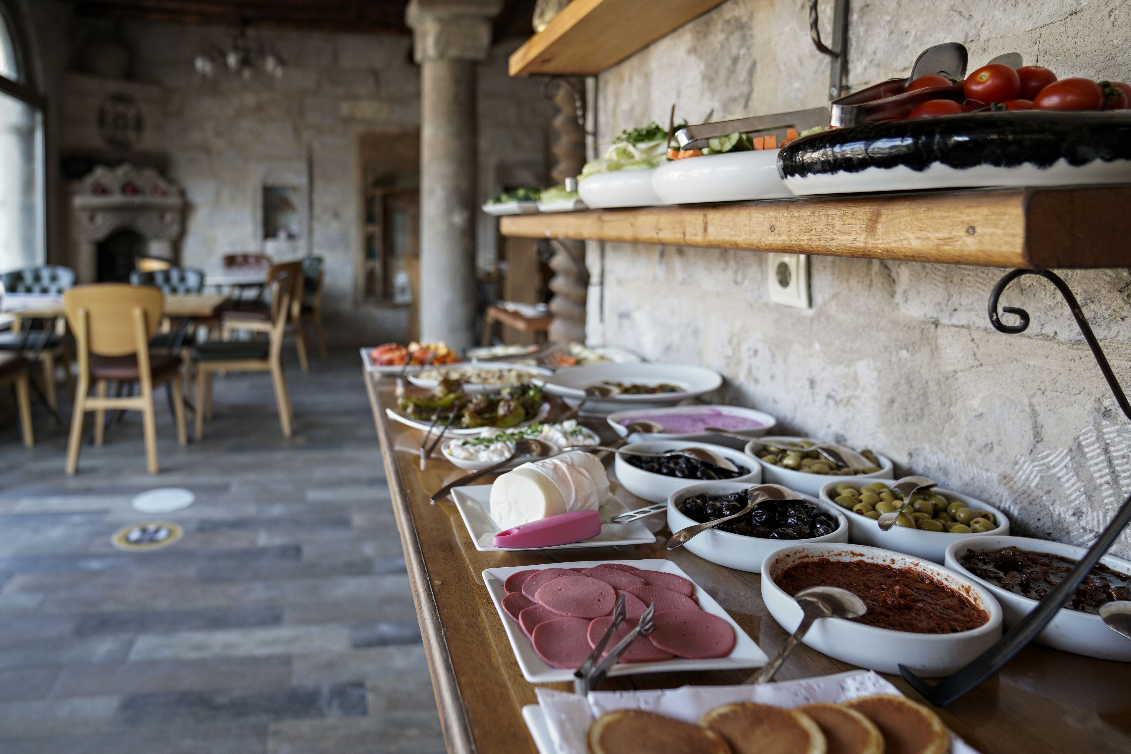 Une table de buffet proposant une variété de plats, ainsi qu’un intérieur rustique avec des murs en pierre et des meubles en bois.