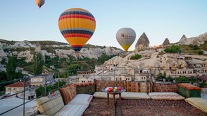 Terraza en la azotea con vistas a un paisaje montañoso y globos aerostáticos.