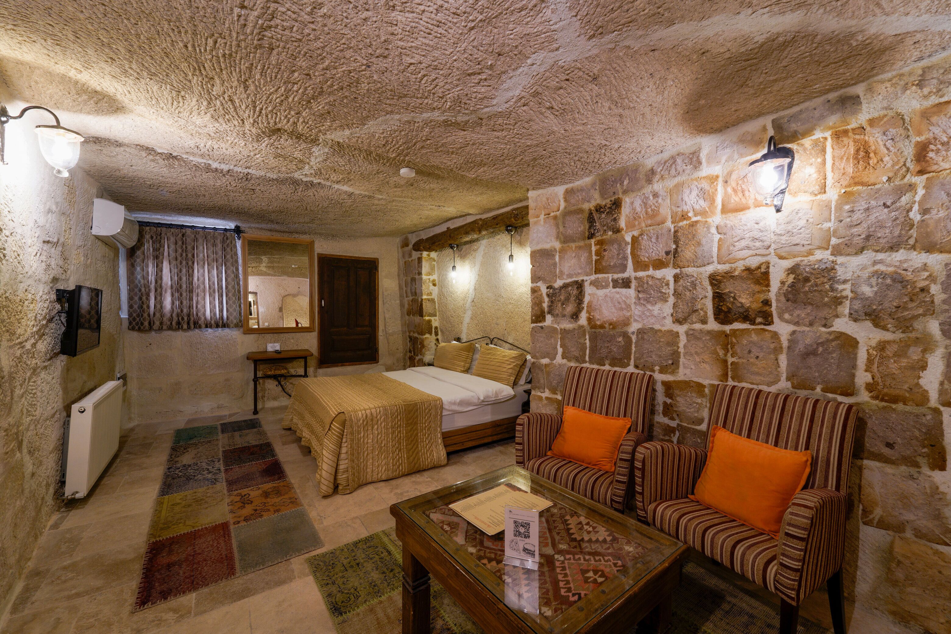 A room with a stone wall, a bed, a sofa, and a coffee table.