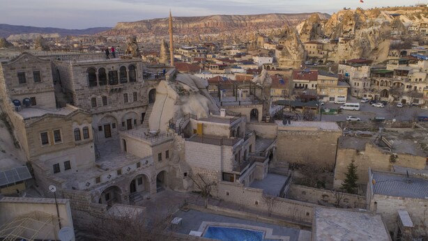 Un edificio histórico de piedra con varios niveles, un patio central y vistas del área urbana circundante.
