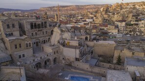 Un edificio histórico de piedra con varios niveles, un patio central y vistas del área urbana circundante.