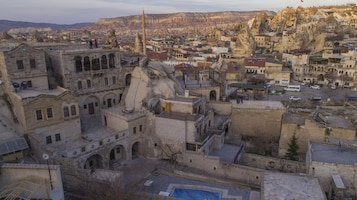 Un edificio histórico de piedra con varios niveles, un patio central y vistas del área urbana circundante.