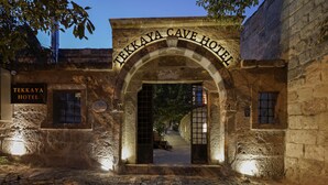 La entrada al Tekkaya Cave Hotel, con paredes de piedra y un camino adoquinado.