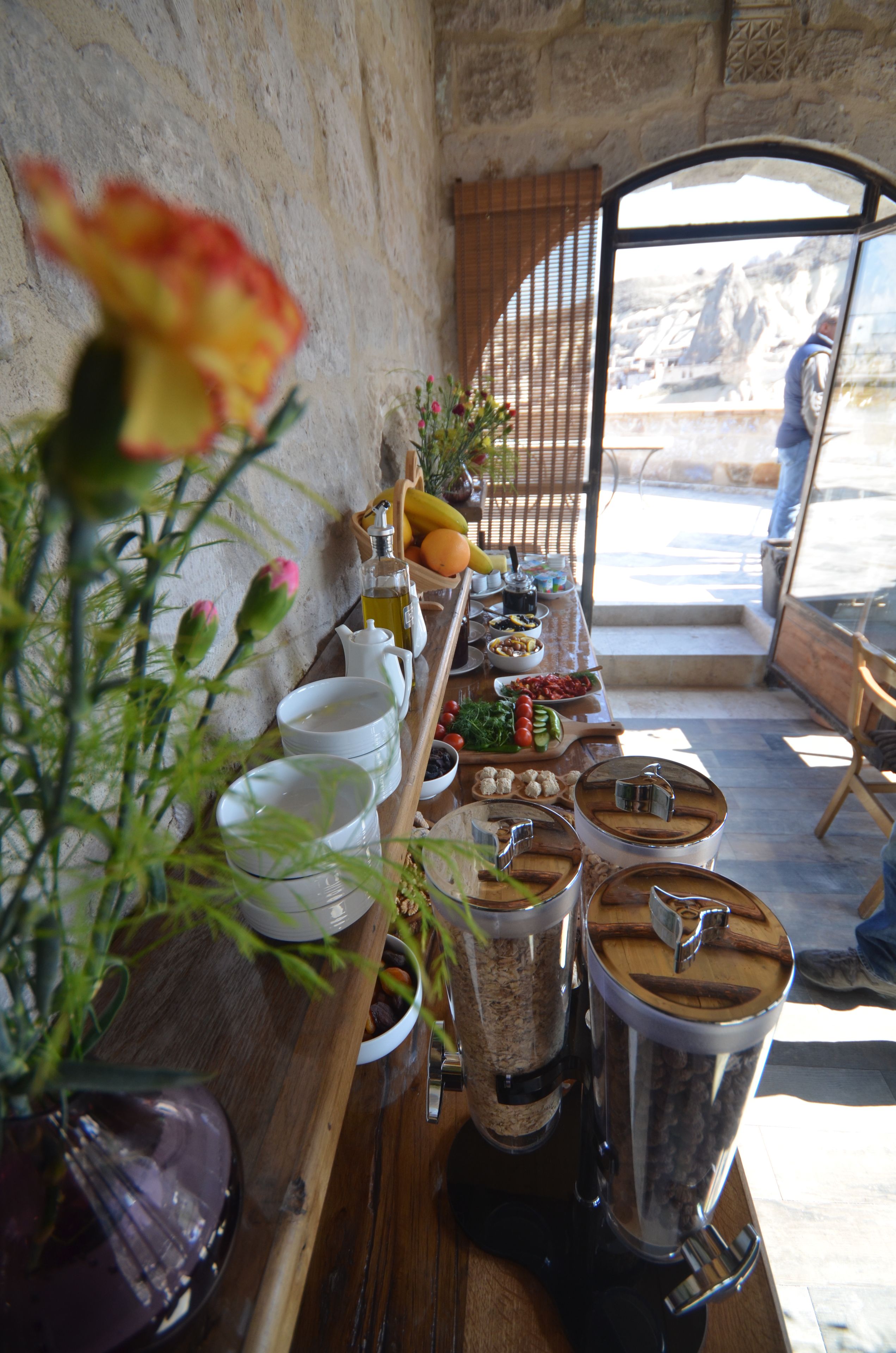 A breakfast table with various food items and a view of a mountainous landscape through a window.