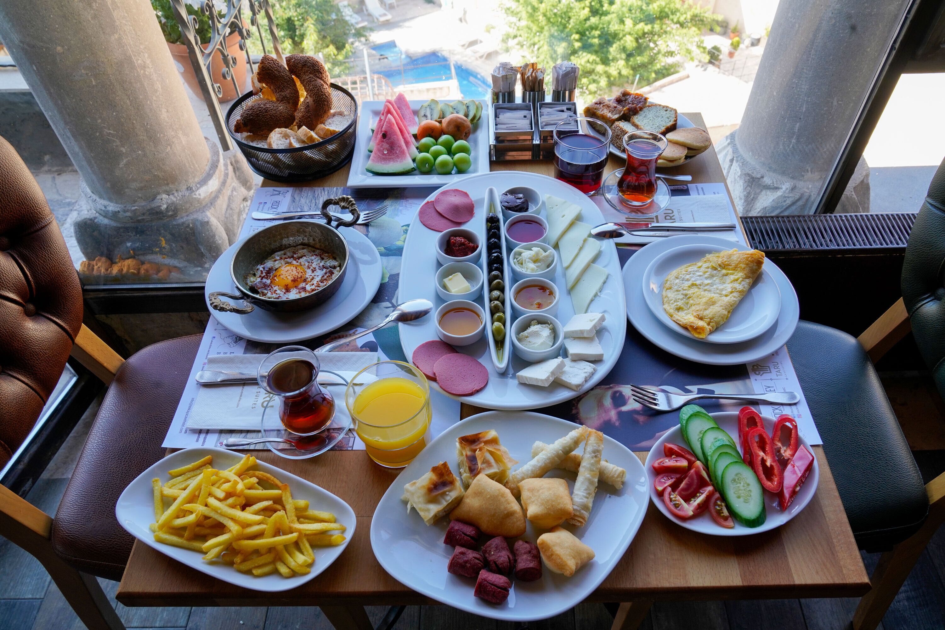 Una mesa dispuesta con diversos alimentos para el desayuno, como huevos, pan, frutas y bebidas.