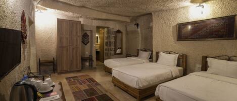 A room with two wooden beds, a wooden wardrobe, a small table with a kettle, and a patterned rug.