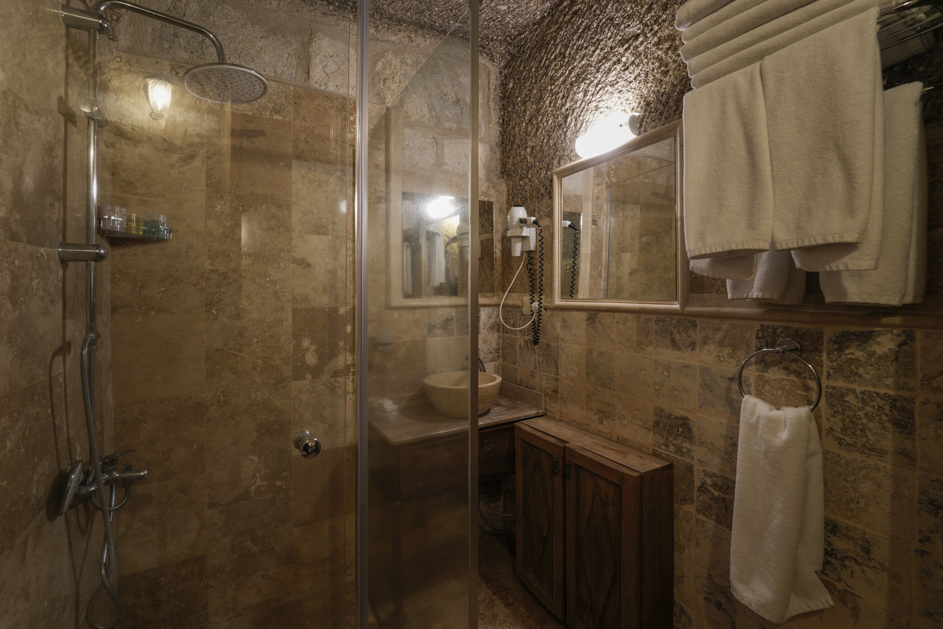 A bathroom with a glass-enclosed shower, a sink, and a wooden cabinet.