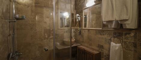 A bathroom with a glass-enclosed shower, a sink, and a wooden cabinet.