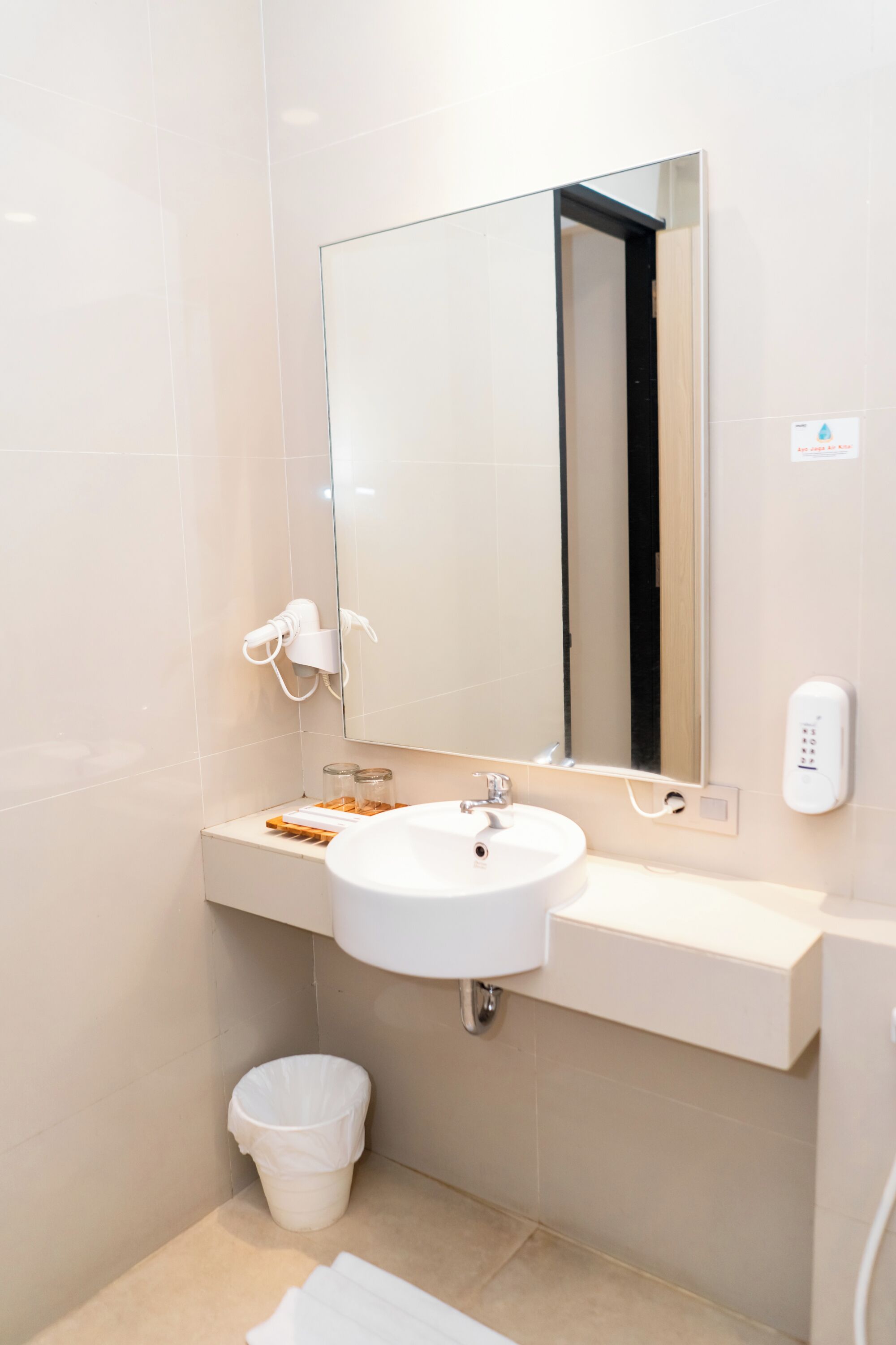 A bathroom with a white sink, mirror, and a hand dryer.