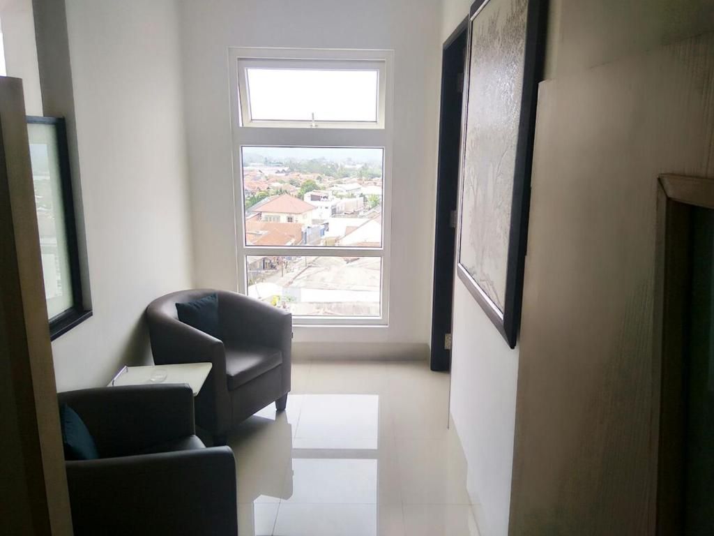 Una habitación con un ventanal grande, una silla y un cuadro en la pared.