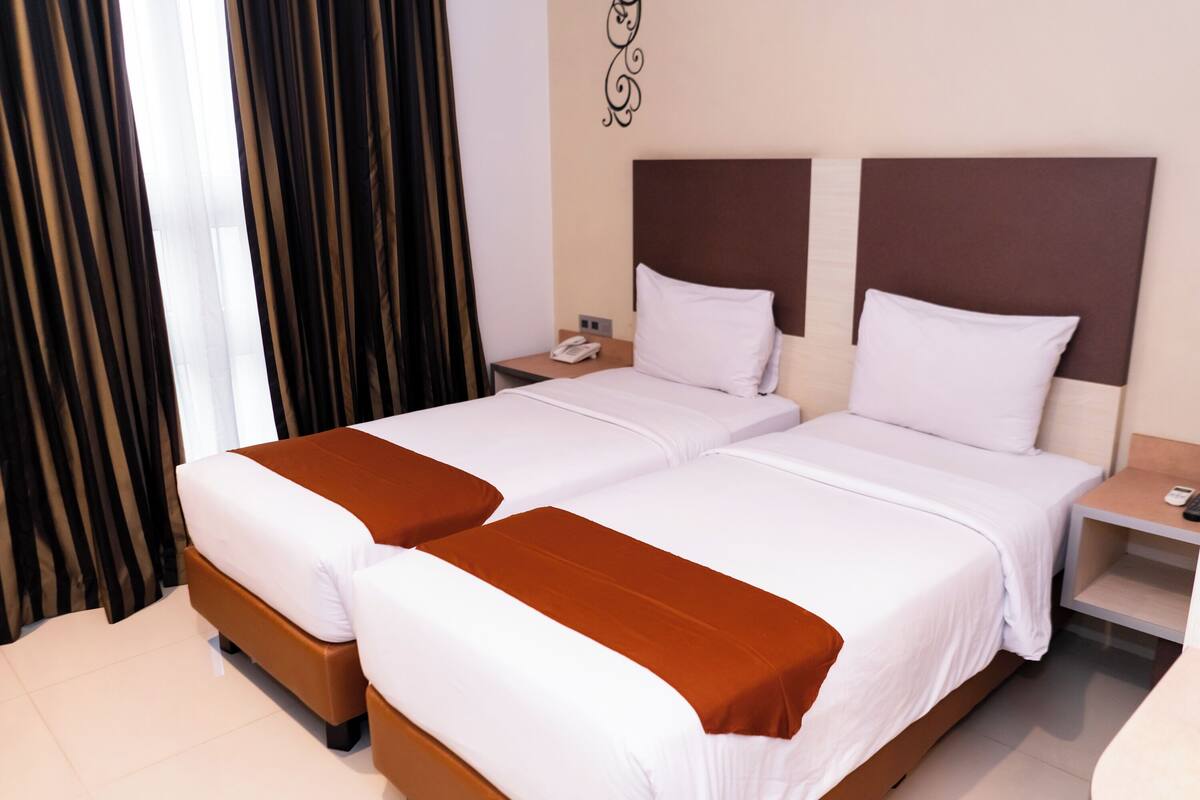 A hotel room with two beds, a nightstand, and a wall decoration.