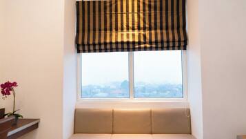 A window with a striped valance, a cushioned bench, and a potted plant.