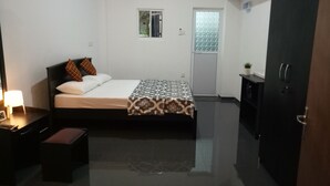 A modern hotel room with a bed, bedside table, lamp, and a wardrobe. - House Of Seya (Negombo)