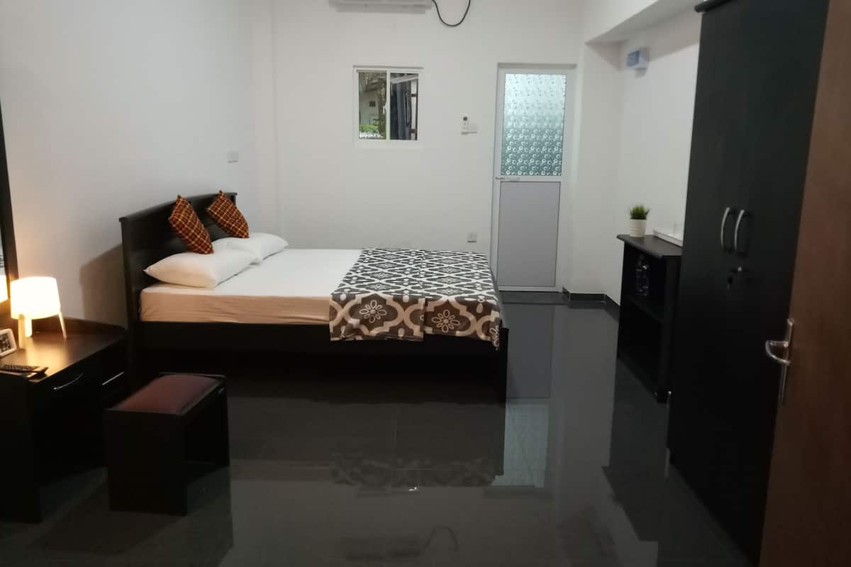 A modern hotel room with a bed, bedside table, lamp, and a wardrobe.