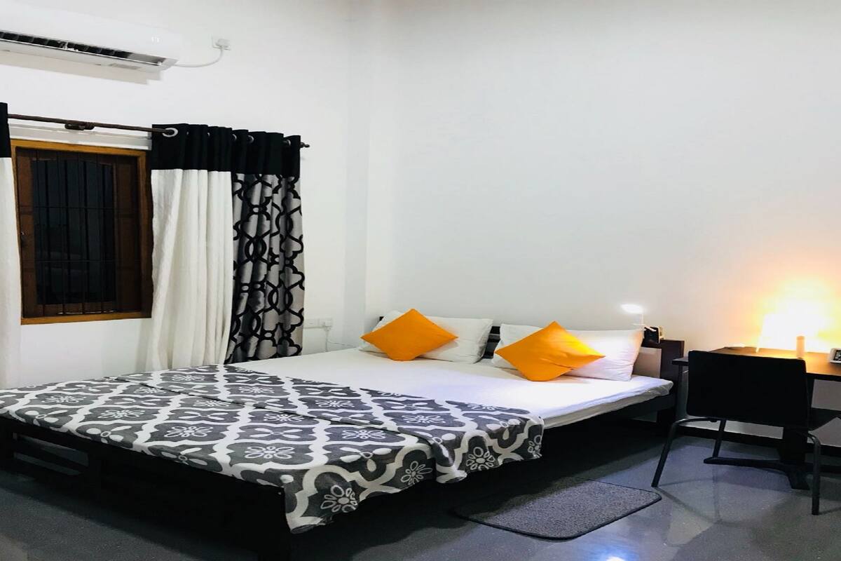 A neatly arranged hotel room with a bed, a desk, and a chair.