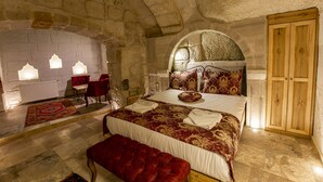 Dormitorio con paredes de piedra, cama, banco y armario de madera.