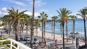 A beachfront promenade with palm trees, beachside seating, and a view of the sea.