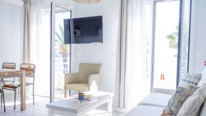 A bright living room with a white sofa, a coffee table, and a TV mounted on the wall.