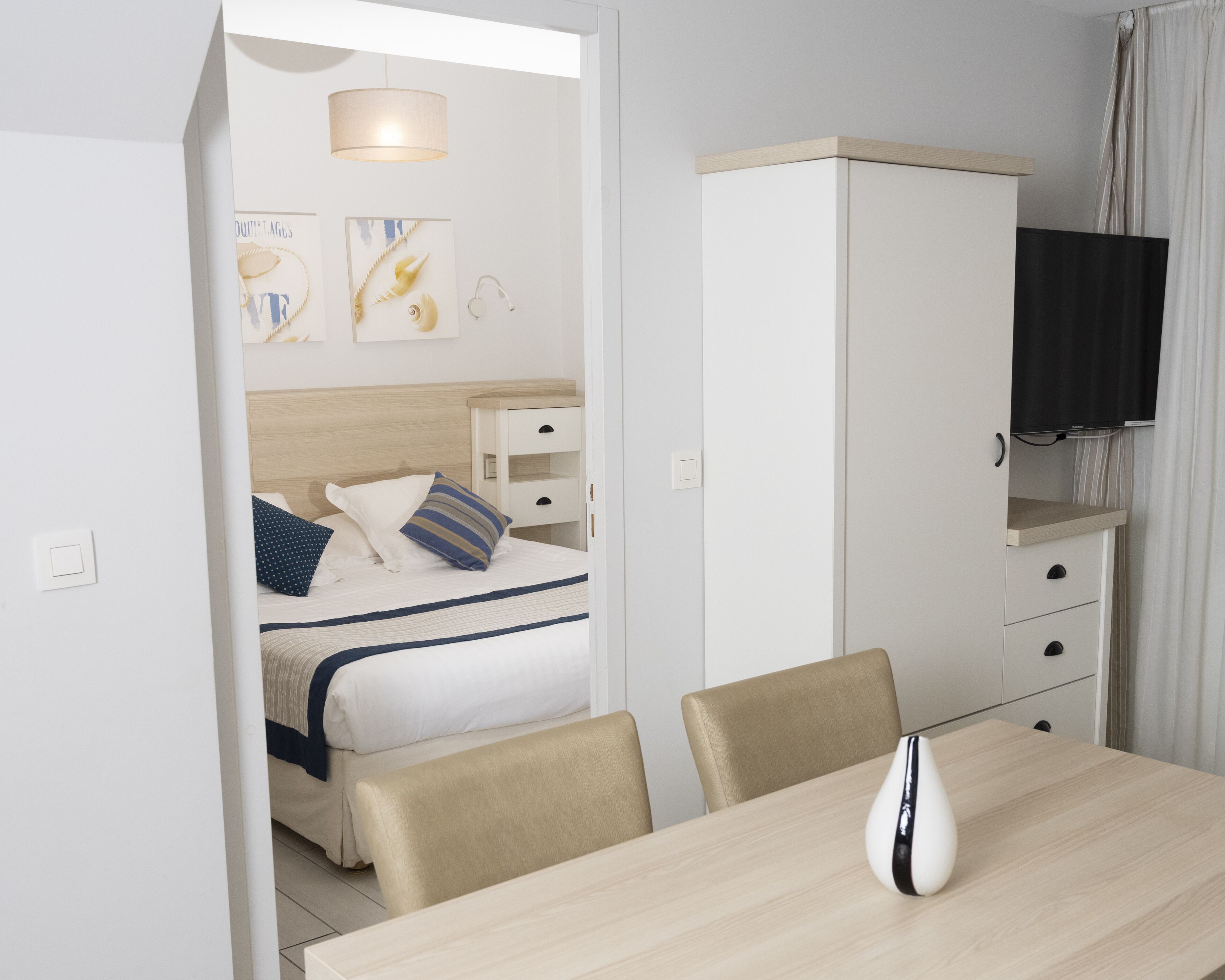 Hotelkamer met een bed, nachtkastjes, een kledingkast, een televisie en een zithoek met stoelen en een tafel.