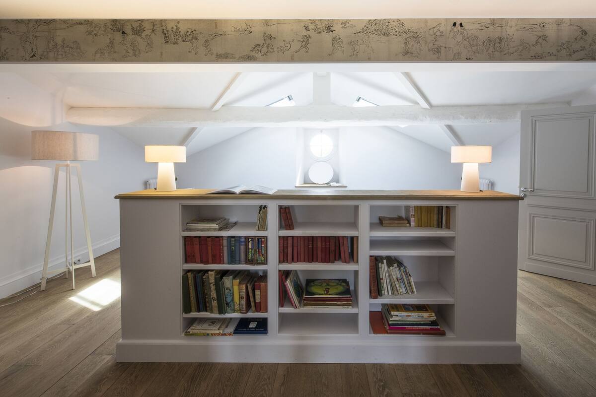 A reading nook with a bookshelf, two lamps, and a skylight.