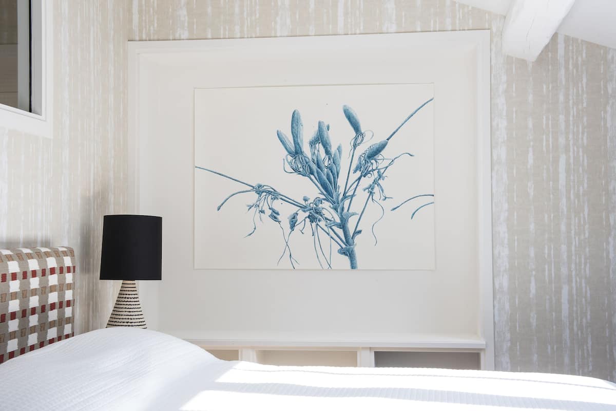 A bedroom with a bed, a lamp, and a wall-mounted artwork.