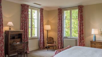 A bedroom with a bed, a desk, a chair, and two lamps.