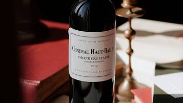 A bottle of Chateau Haut-Bailly wine on a table with books and a candle.