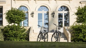 A building with three arched windows and a staircase leading to the entrance. - Haut-Bailly - La Chartreuse - Anciennement Château Le Pape (Leognan)