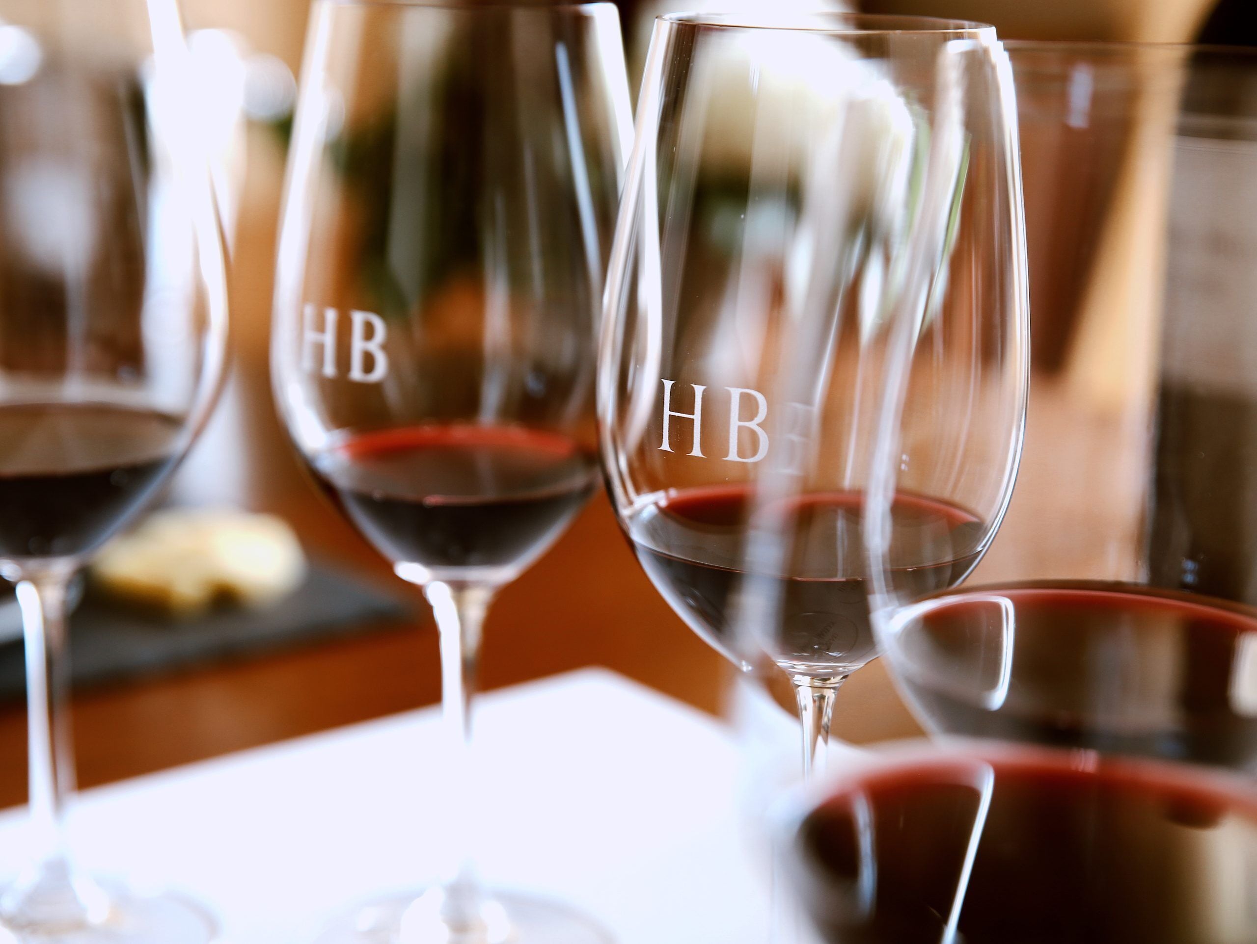 Trois verres à vin, portant les lettres « HB » en relief, sont posés sur une table.
