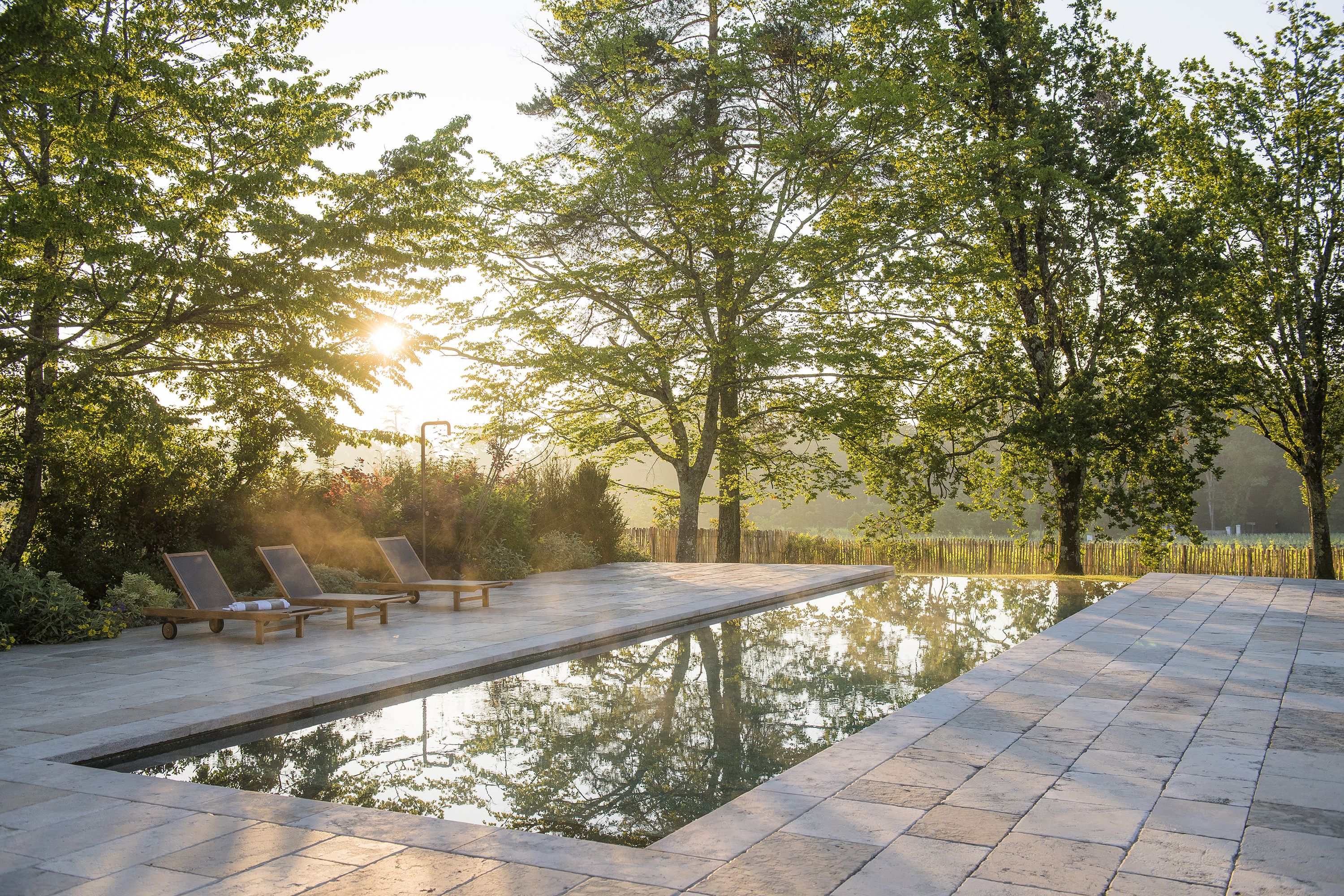 A serene outdoor swimming pool area with lounge chairs and a clear view of the surrounding trees.