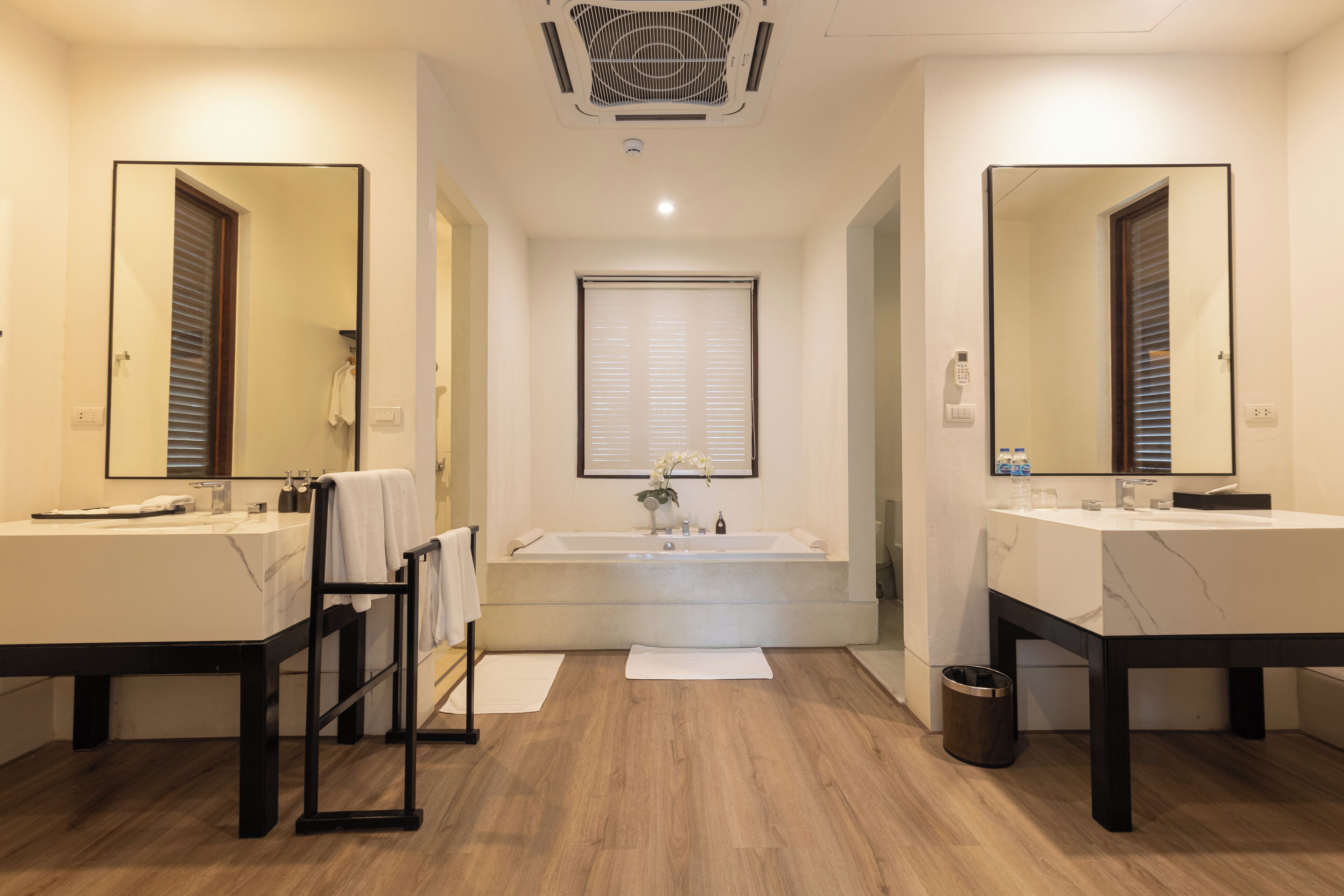A modern bathroom with two sinks, a large bathtub, and a mirror above the bathtub.
